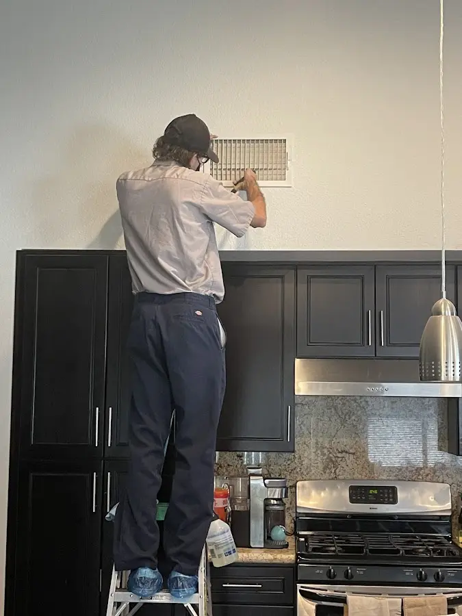 Technician inspecting an air vent during HVAC service in Denton